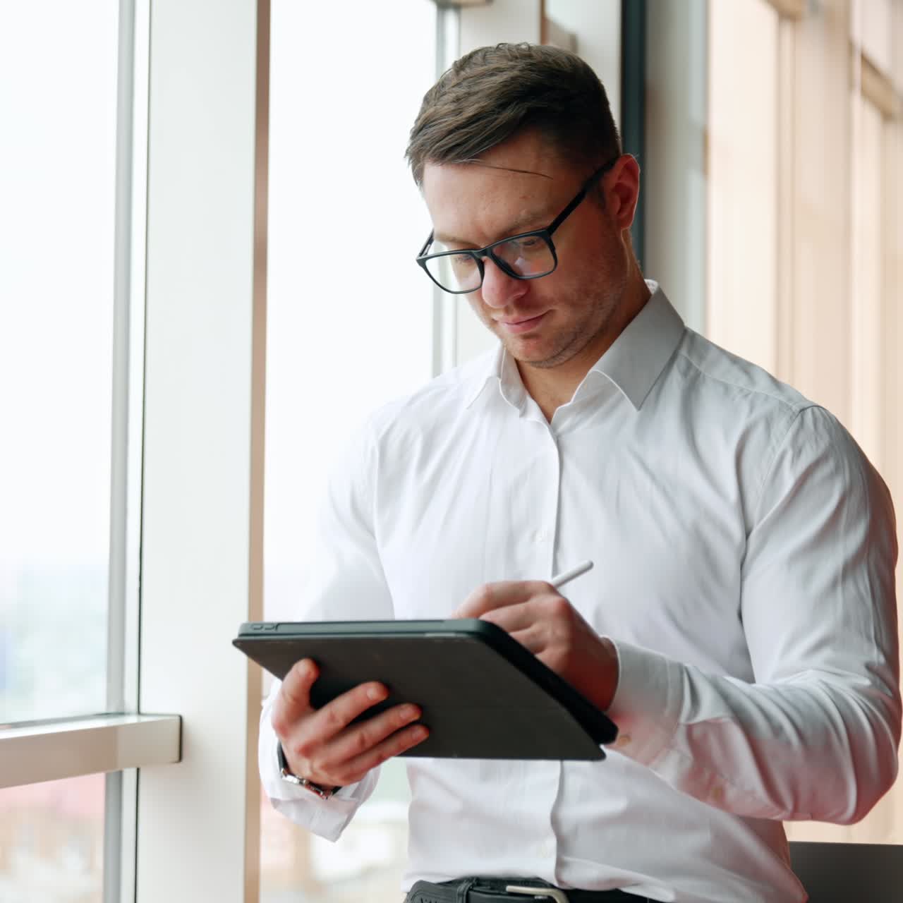 Pensive Caucasian businessman holding an I-pad and stylus pencil. Man looking at window and having the idea