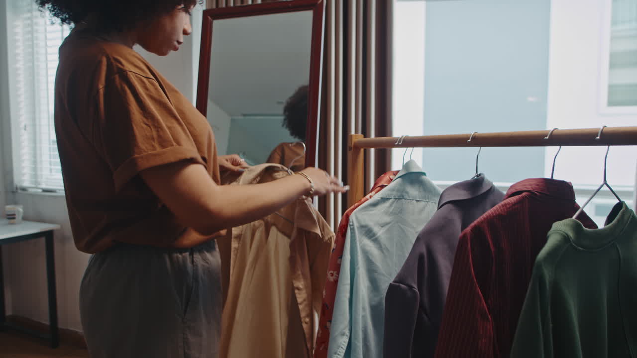 Young Woman Choosing Outfit for Work Standing near Mirror