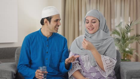 happy muslim husband giving medicine to his wife