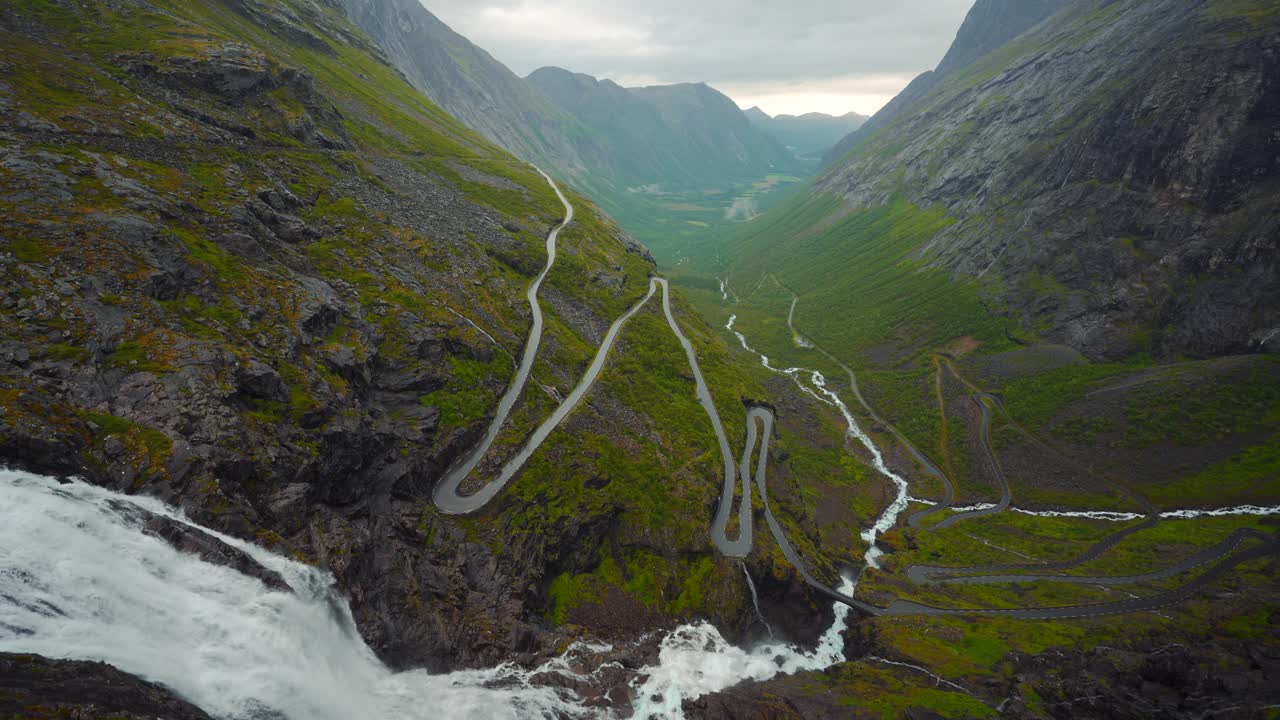 Breathtaking Aerial View of Winding Mountain Road and Waterfall in Norway