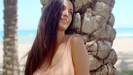 Pretty-Woman-Leaning-Against-Beach-Palm-Tree-Trunk