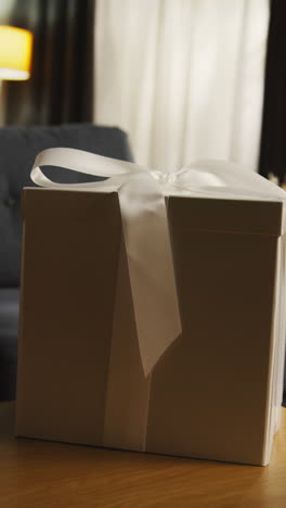 vertical video of present in gift wrapped box decorated with ribbon on table in lounge 1