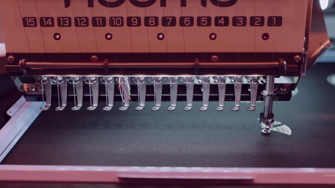 automatic embroidery machine with 15 needles sewing on dark textile