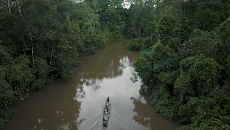 ascending aerial view showing people sitting in kayak boat and cruising in amazon rainforest