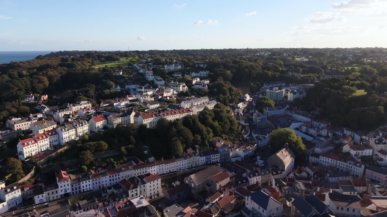 Filmato aereo di altissima qualità su St Peter Port, Guernsey, ripreso da un drone in direzione sud, che mostra case ed edifici disposti a terrazze, con il territorio che offre una prospettiva unica e una luce meravigliosa