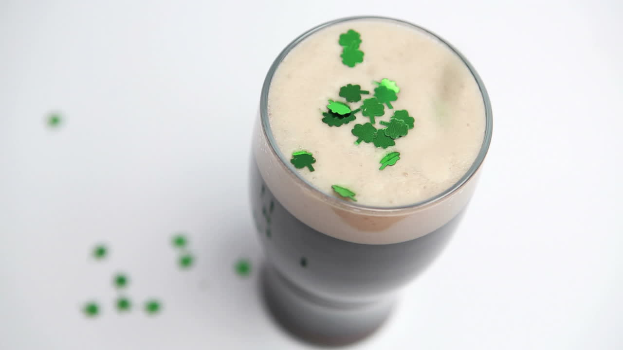 Shamrock confetti falling on pint of stout