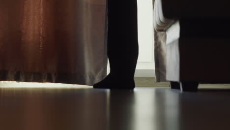 silhouette of man in pan suit stands by window in hotel room