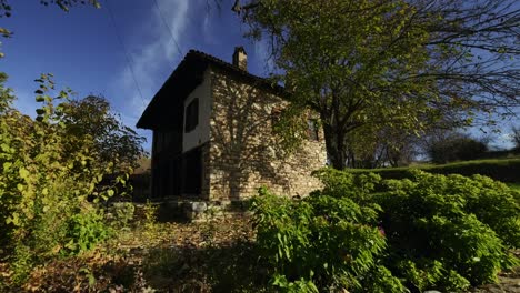 la cámara se acerca a una antigua casa de estilo turco, de medio ladrillo, con un árbol a un lado