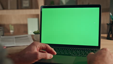 businessman hand touching green screen laptop touchpad at workplace close up.