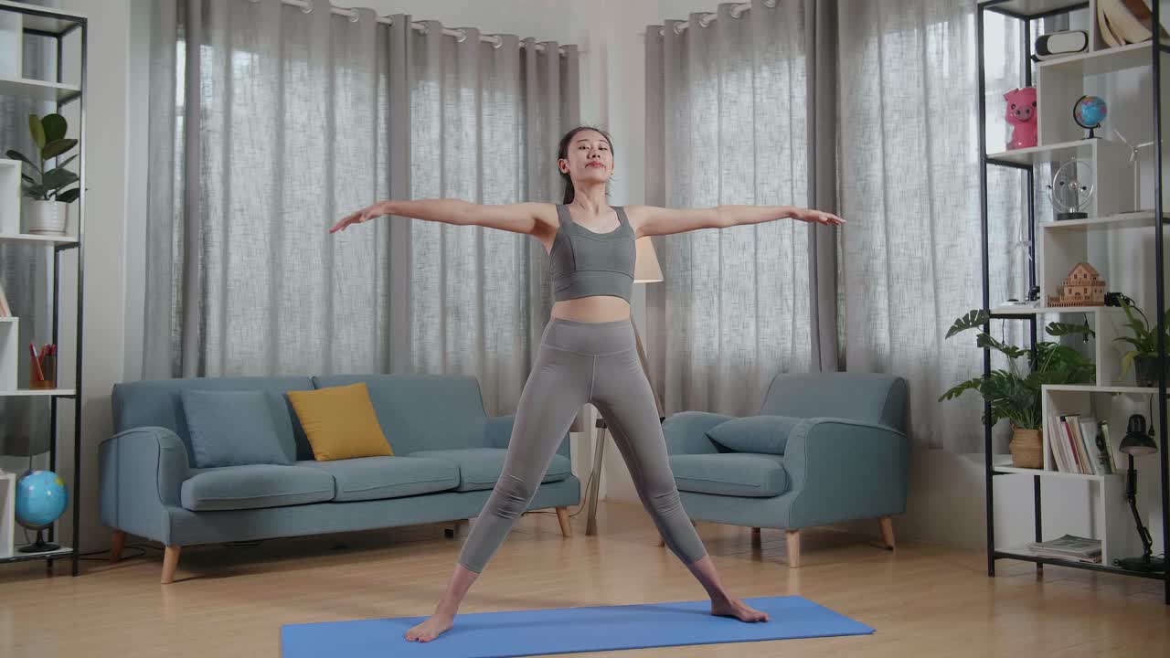 집에서 운동을 가르치는 동안 말을 하고 스트레칭하는 스포츠 옷을 입은 젊은 아시아 트레이너 여성의 전체 시각