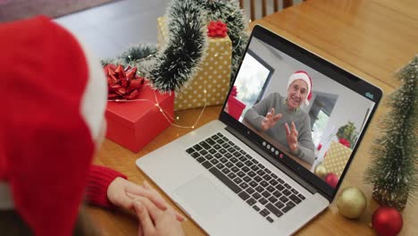 Happy-caucasian-woman-on-video-call-with-grandfather-at-christmas-time