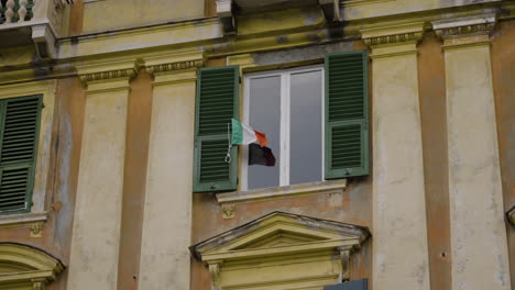 still shot of the italy flag waving in the exterior of an apartment