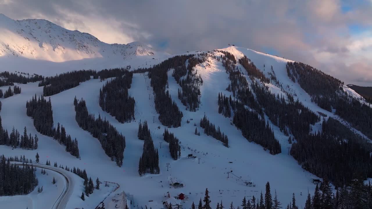 Winter spring sunset Arapahoe Basin Basin Abay Ski Resort Colorado aerial drone last light golden hour groomed ski trail runs chairlift main lodge Base Area parking lot summit county circle left