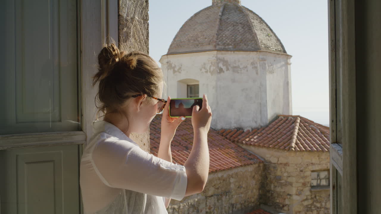 mujer feliz usando un teléfono inteligente tomando fotos disfrutando de compartir experiencias de viajes de vacaciones de verano fotografiando una hermosa vista panorámica en el balcón con gafas de sol
