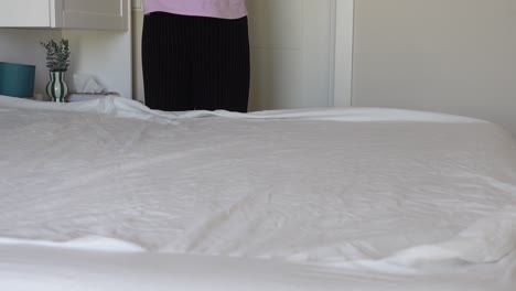 woman making bed in bedroom