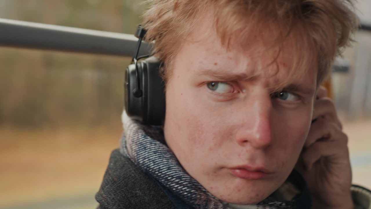 Créateur caucasien jette un regard en arrière, expression soudaine d'alerte et de malaise, serrant sa prise sur les écouteurs, traits du visage tendus, environnement de navetteur, paysage d'automne défilant, conteur pressentant une interruption.