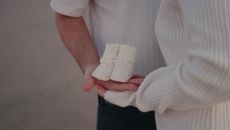 close up de padres sosteniendo botas de bebé, simbolizando el amor y la anticipación de una nueva vida