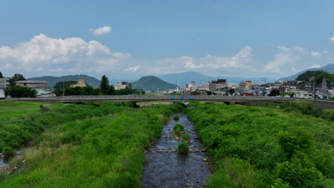 Aerial-view-low-over-the-Yomase-river,-sunny,-summer-day-in-Yamanochi,-Japan