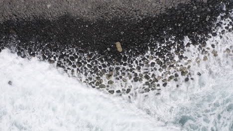 toma de vista superior de drones de 4k de olas oceánicas que se estrellan en una costa con rocas oscuras en australia