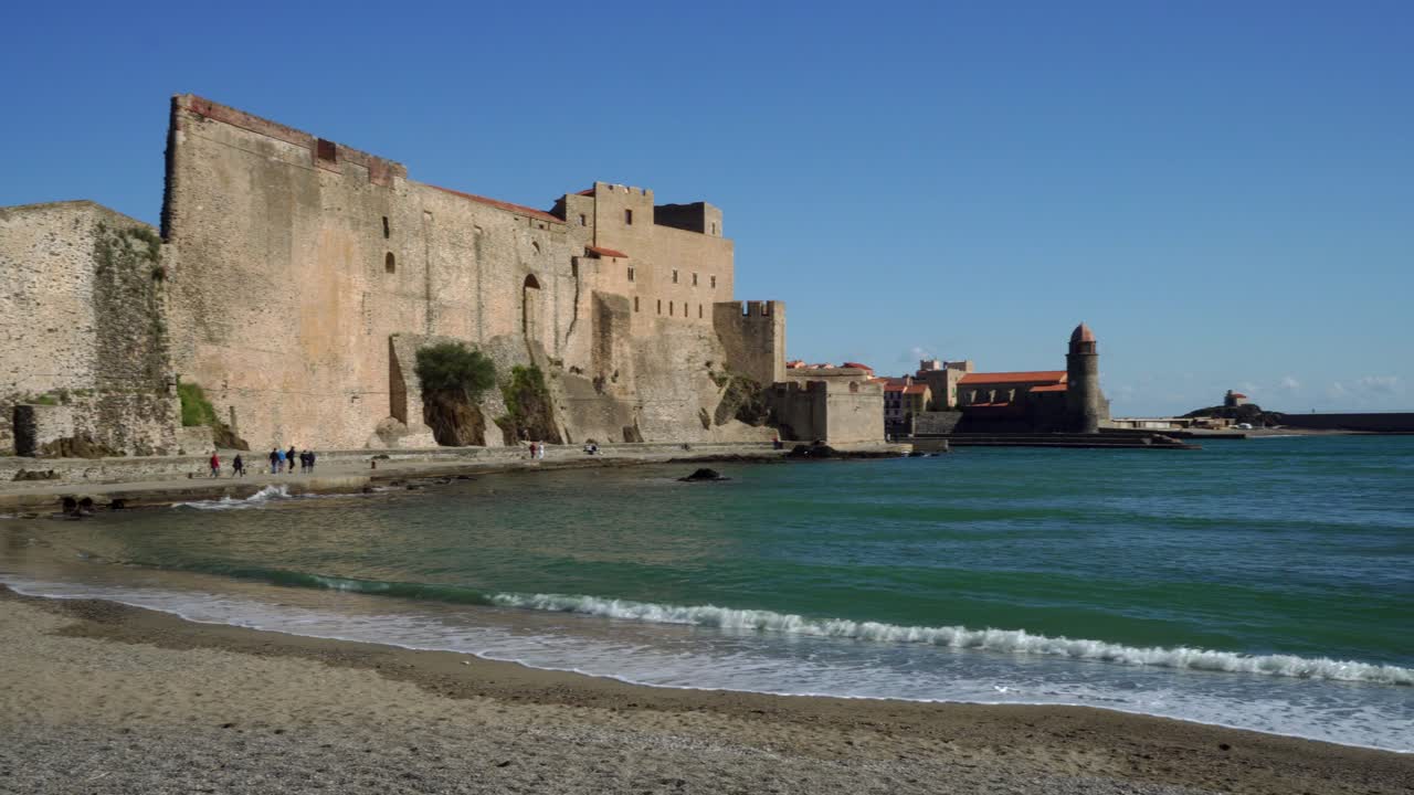 La spiaggia, la fortezza e il centro storico di Collioure durante venti forti in una giornata calda e luminosa