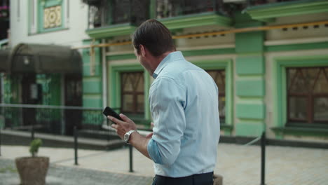 back view businessman celebrating at street. man dancing in stylish shirt