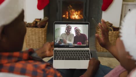 Pareja-Afroamericana-Usando-Una-Computadora-Portátil-Para-Una-Videollamada-Navideña-Con-Una-Familia-Sonriente-En-La-Pantalla