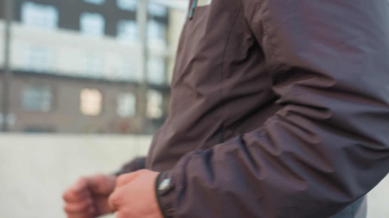 동적인 팔 움직임으로 겨울 재을 입고 조하는 남자의 클로즈업, 액션, 피트니스, 그리고 결단력을 보여주는, 오피스 빌딩을 특징으로하는 도시 배경에 설정