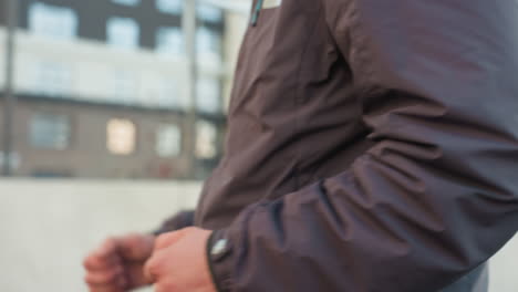 primer plano de un hombre corriendo con una chaqueta de invierno con movimientos dinámicos de los brazos, mostrando acción, aptitud y determinación, en un fondo urbano con un edificio de oficinas