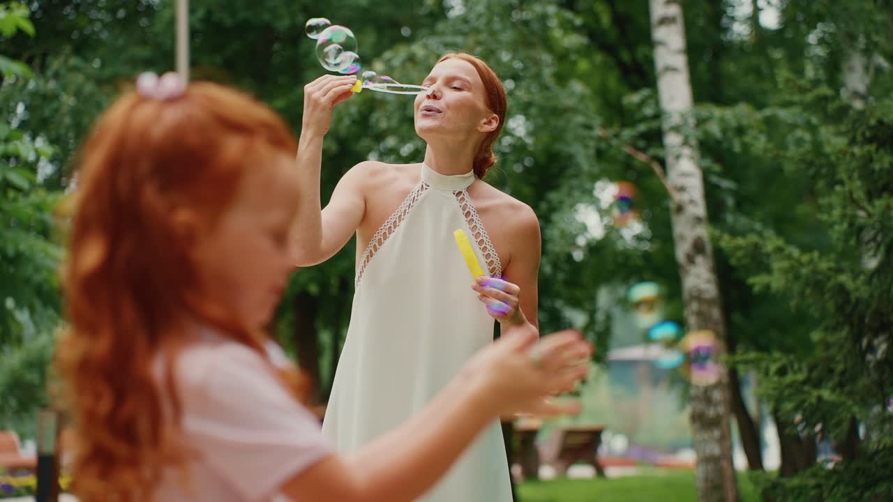 madre e hija jugando con burbujas en el parque