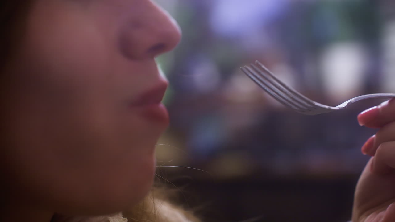 Close-up of lady enjoying creamy croissant topped with whipped cream and fruit, taking a bite with fork in cozy cafe. Soft lighting and blurred background create relaxed atmosphere