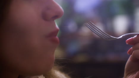 close-up of lady enjoying creamy croissant topped with whipped cream and fruit, taking a bite with fork in cozy cafe. soft lighting and blurred background create relaxed atmosphere