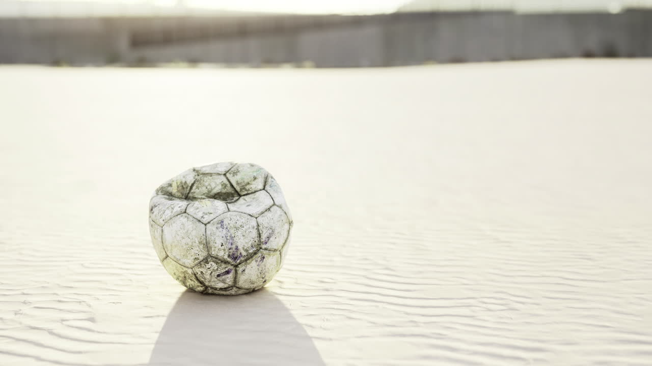 Forgotten soccer ball among shifting sands on a sunlit beach