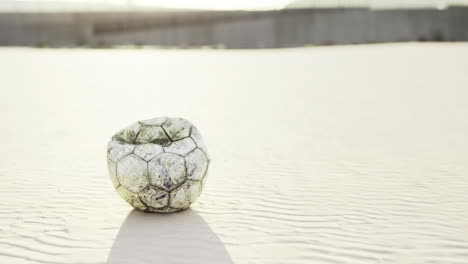 forgotten soccer ball among shifting sands on a sunlit beach