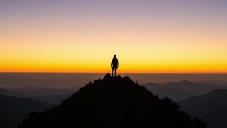 a solitary figure stands tall on a mountain peak at sunrise, silhouetted against a breathtaking gradient of warm hues, capturing the beauty and tranquility of nature