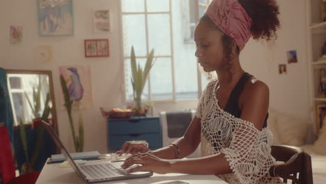 young girl using laptop and making notes at home