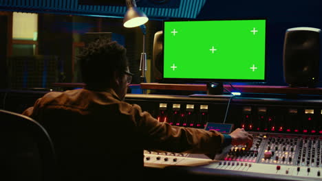 ingeniero de audio afroamericano usa pantalla verde en su pc