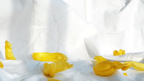 elegant skincare product photography with yellow petals and white fabric