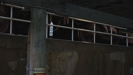 Train-Undercarriage-Passing-Station,-Slow-Motion-Pan-Shot