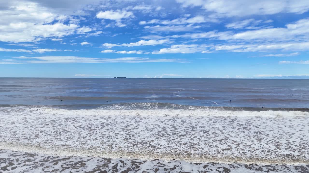 Gentle ocean waves approach sandy shore, wide angle, natural daylight, calm coastal atmosphere, static camera