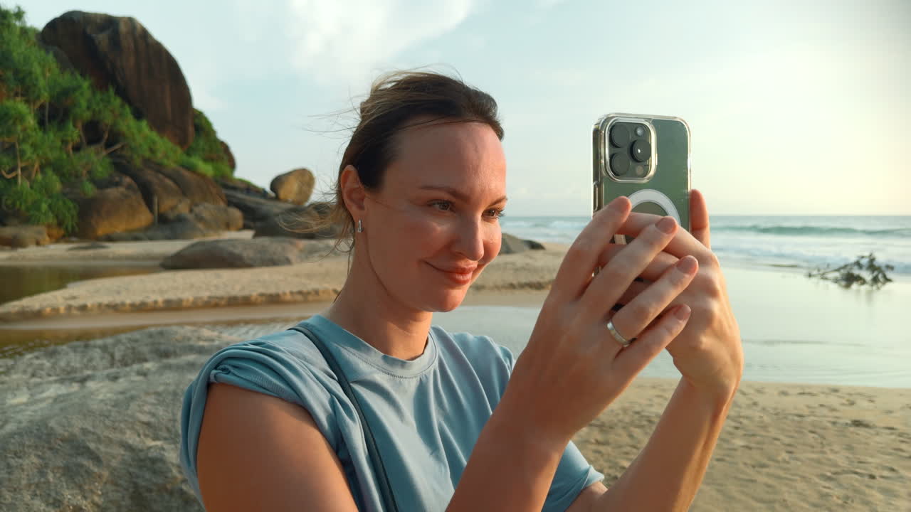 mujer tomando una foto en una playa al atardecer