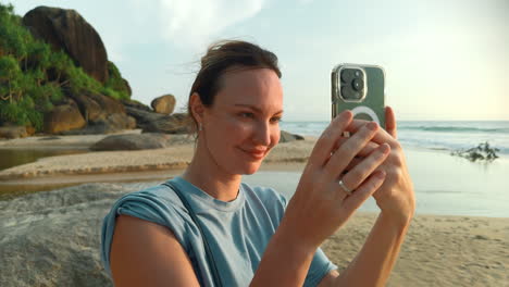 woman taking a photo on a beach at sunset