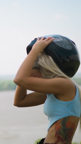 happy man and young woman in blue top take off protective moto helmets standing against large picturesque lake on spring day slow motion