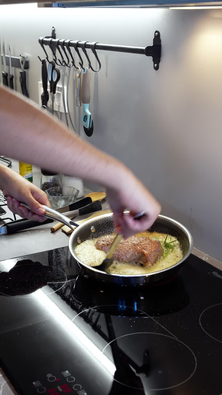 Cooking ribeye steak in a pan, sizzling sounds in a kitchen setting