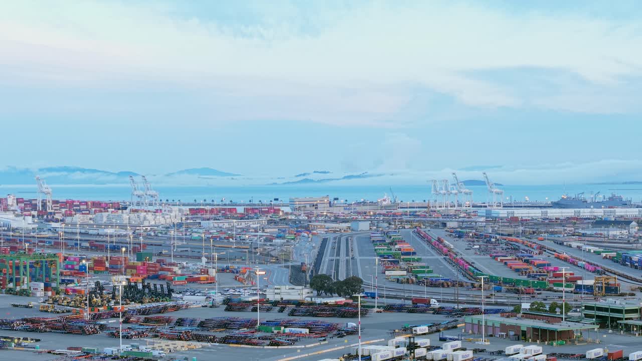 The drone pans across a bustling harbor scene filled with industrial life and coastal energy.