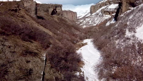 escaleras que conducen a una ruta de senderismo en un cañón escarpado debajo de acantilados y montañas nevadas