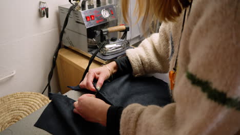seamstress sewing button onto clothing top. wide shot