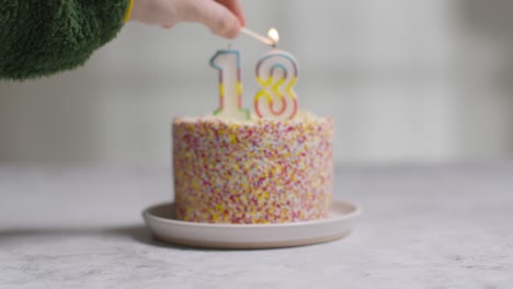 studio shot birthday cake covered with decorations and candle celebrating thirteenth birthday being lit