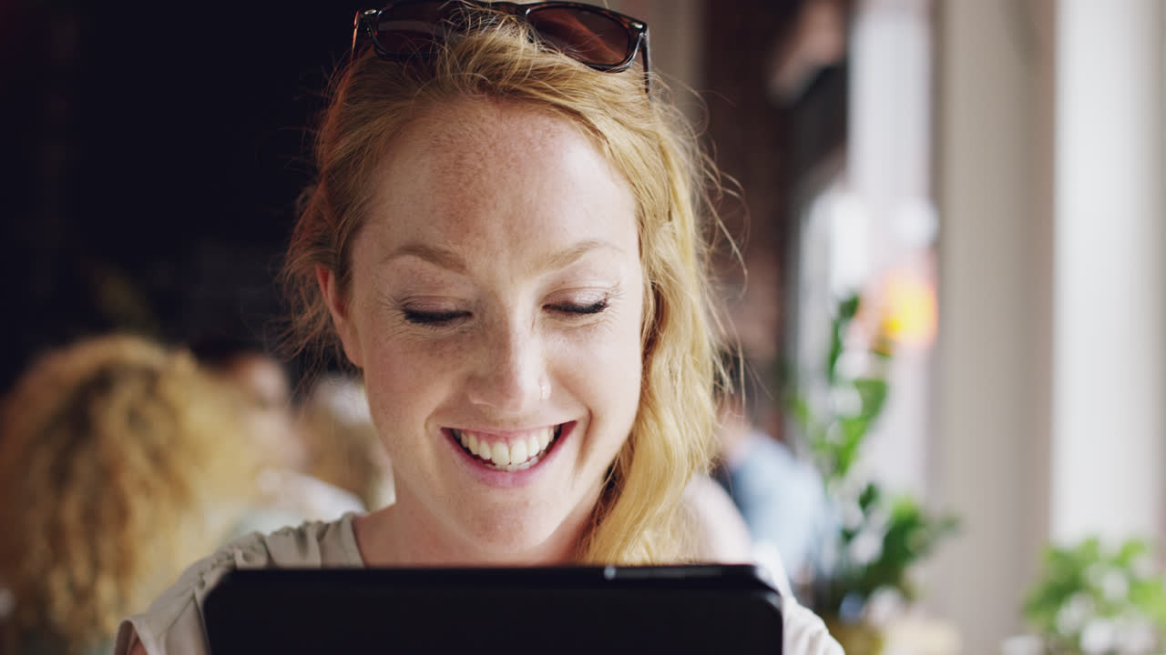 カフェでipadタブレットタッチスクリーンを使用する美しい若い女性