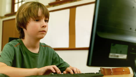 cute little pupil looking at laptop in classroom