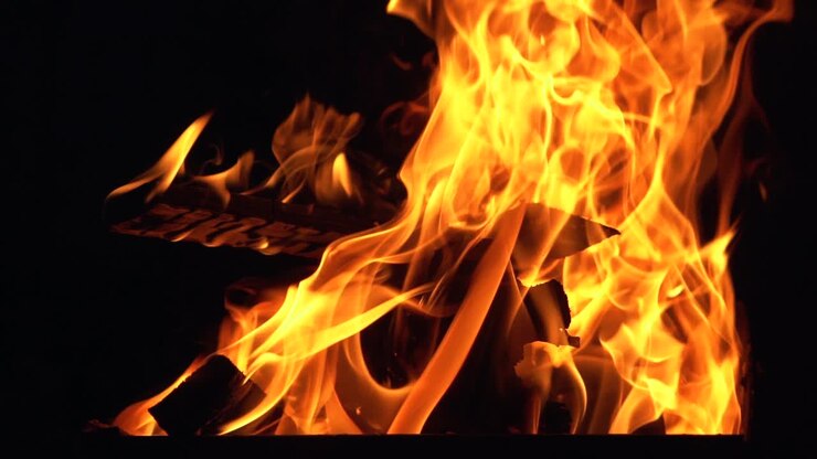 Legna che brucia. Fiamme di fuoco su sfondo nero. Falò. Movimento rallentato